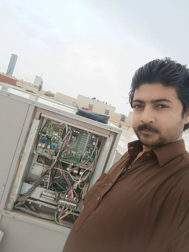 Technician taking a selfie while working on an outdoor electrical panel.