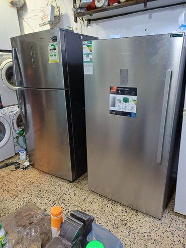 Two silver refrigerators side by side in a room with other appliances.