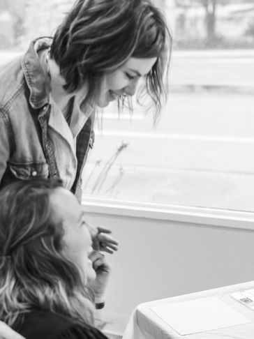 Two women smiling and interacting indoors.