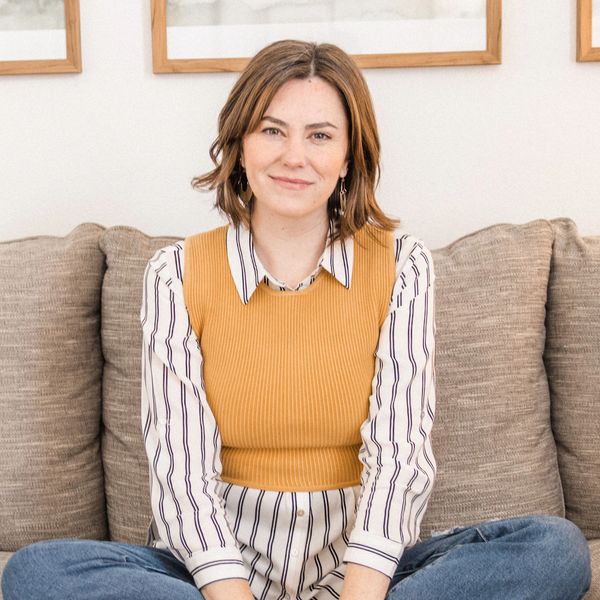 Woman sitting cross-legged on a couch smiling.