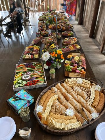 A long table filled with assorted crackers, vegetables, and charcuterie platters.