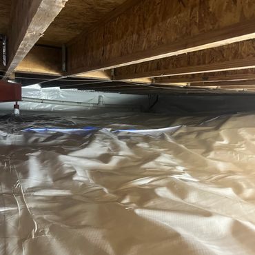 Deep view of a fully rejuvenated crawl space with bright white vapor barrier and mold-remediated woo