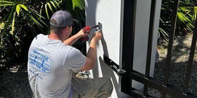 Technician installing a gate latch outdoors.