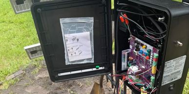 Person wiring an electronic control box outdoors.
