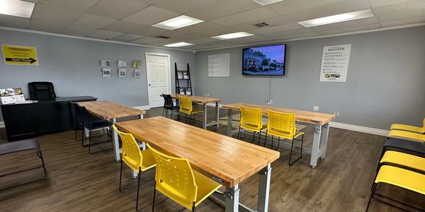 Modern classroom with wooden desks and yellow chairs arranged neatly for real estate certification.