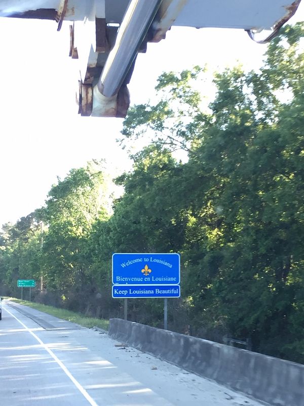 Bucket truck servicing "Welcome To Louisiana" sign.