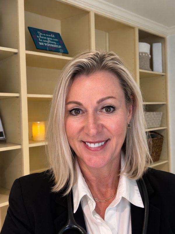 Professional woman with blonde hair smiling in an office setting.