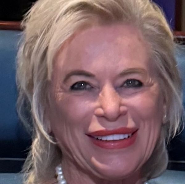 Smiling woman with pearl necklace and blonde hair.