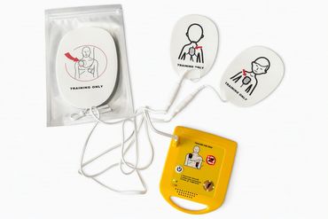 Mini AED training defibrillator with child and adult pads.