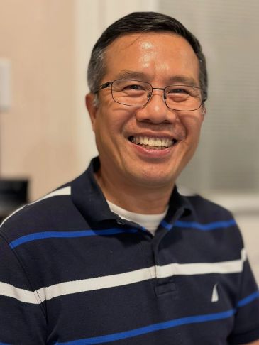 Smiling man wearing glasses and a striped polo shirt.