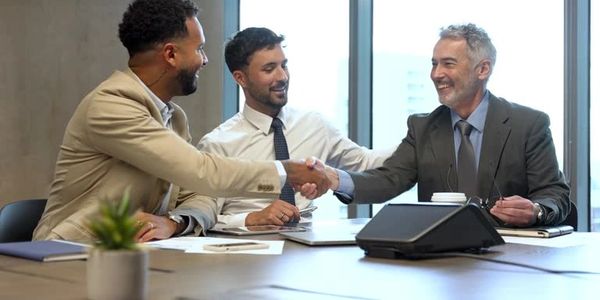 Three businessmen shaking hands in a modern office setting.