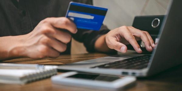 Person making an online payment using a credit card and laptop.