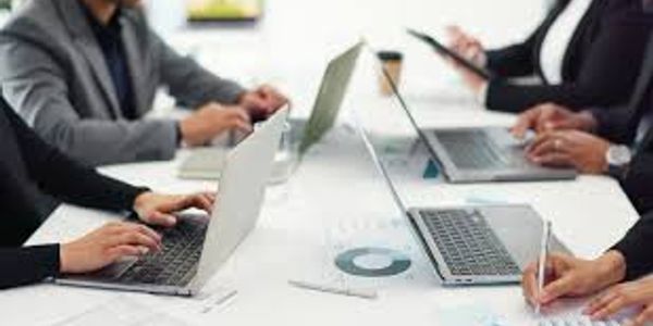People working together on laptops at a meeting table.