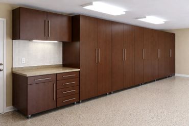 Long row of sleek brown cabinets with a countertop and overhead lighting.