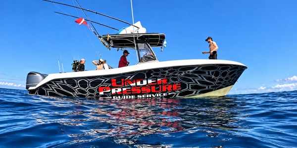 Fishing boat on clear blue ocean with people onboard.