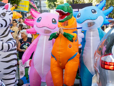 People in colorful animal costumes participate in a lively protest with signs.