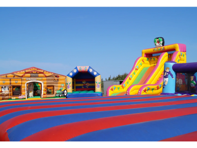 Colorful inflatable bouncy castles and slides under a clear blue sky.