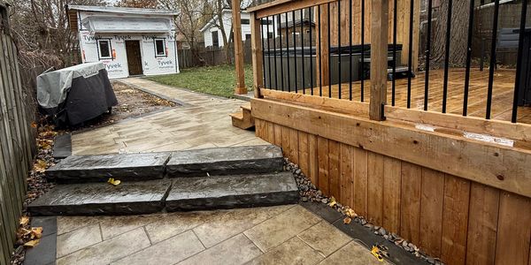 Newly constructed backyard with stone steps and wooden deck.
