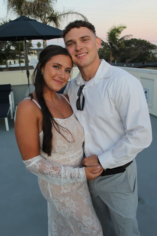 A smiling couple posing together outdoors at sunset.