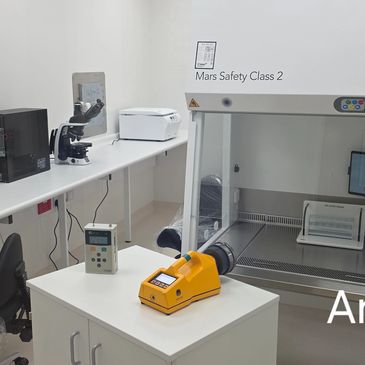 A clean laboratory setup with a microscope, a biosafety cabinet, and electronic devices.
