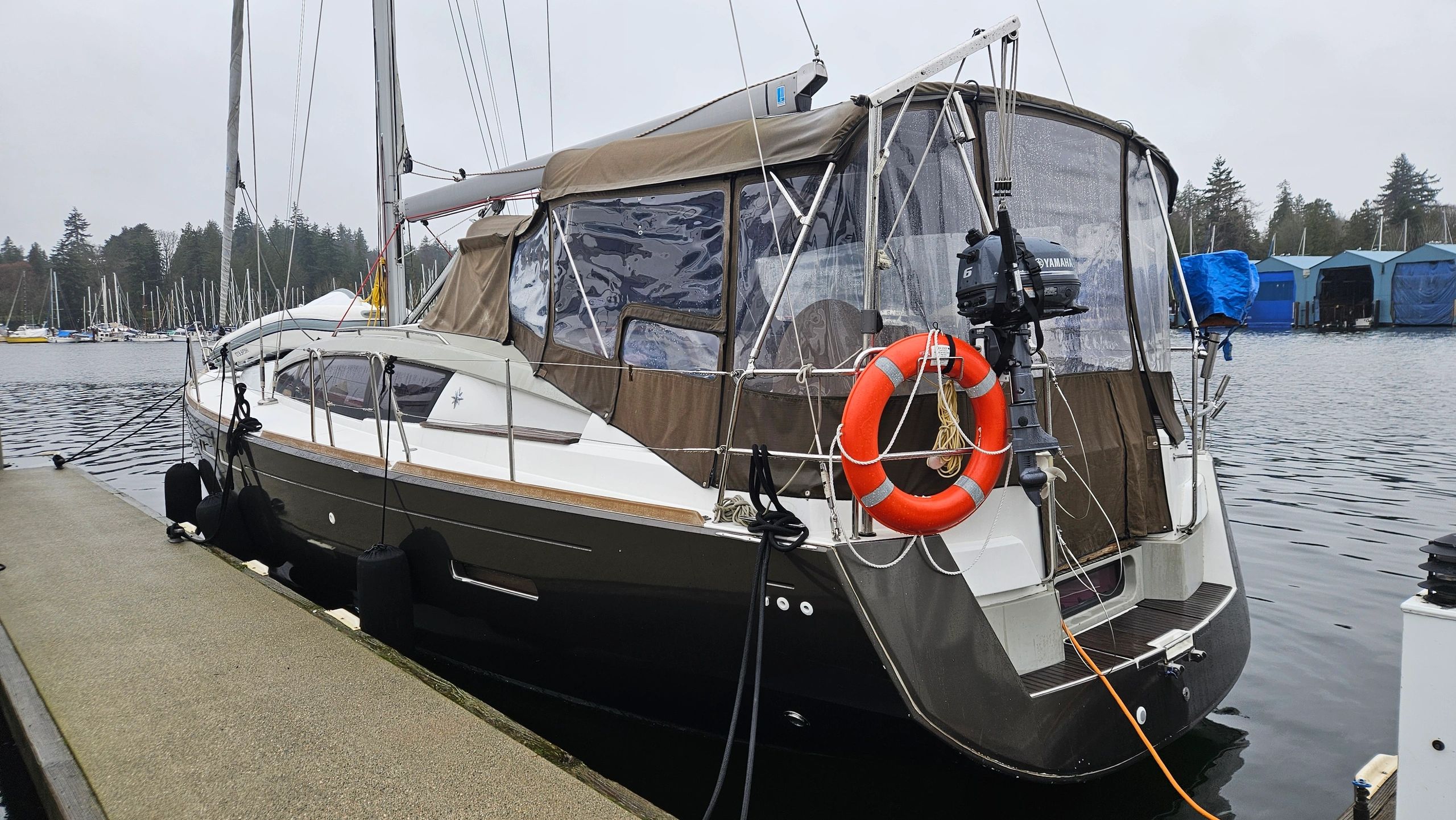 Sailboat docked at a marina on a cloudy day with a life ring attached.
