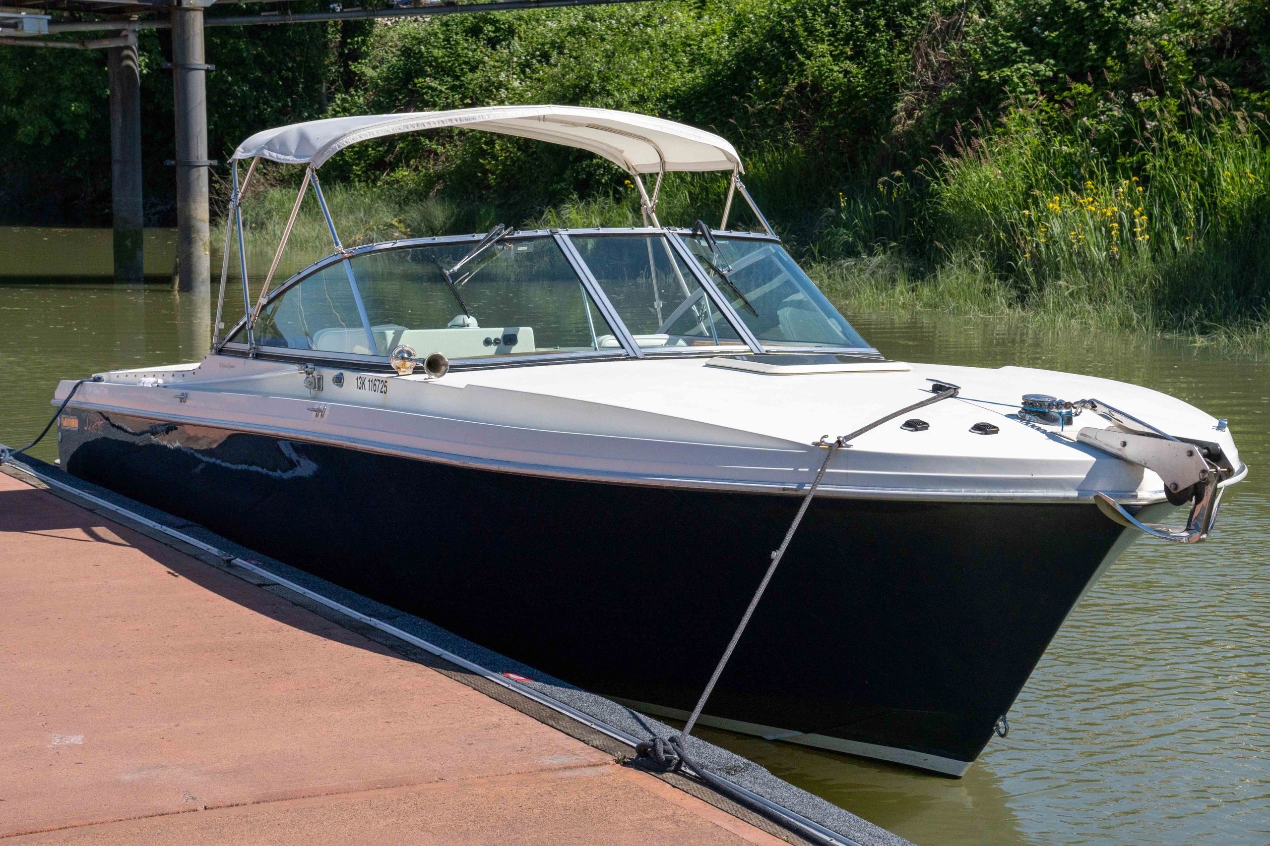 A sleek black and white boat docked by the water's edge.