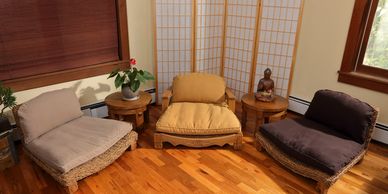 Cozy meditation corner with cushioned floor chairs, wooden tables, and serene decor.