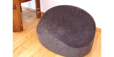 Gray cushioned seat on wooden floor near wooden table.