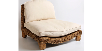 Low woven chair with beige cushions and wooden legs.