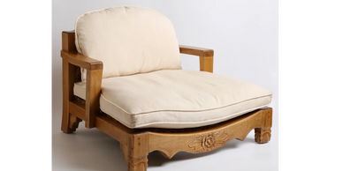 Wooden armchair with cream cushions and floral carving.