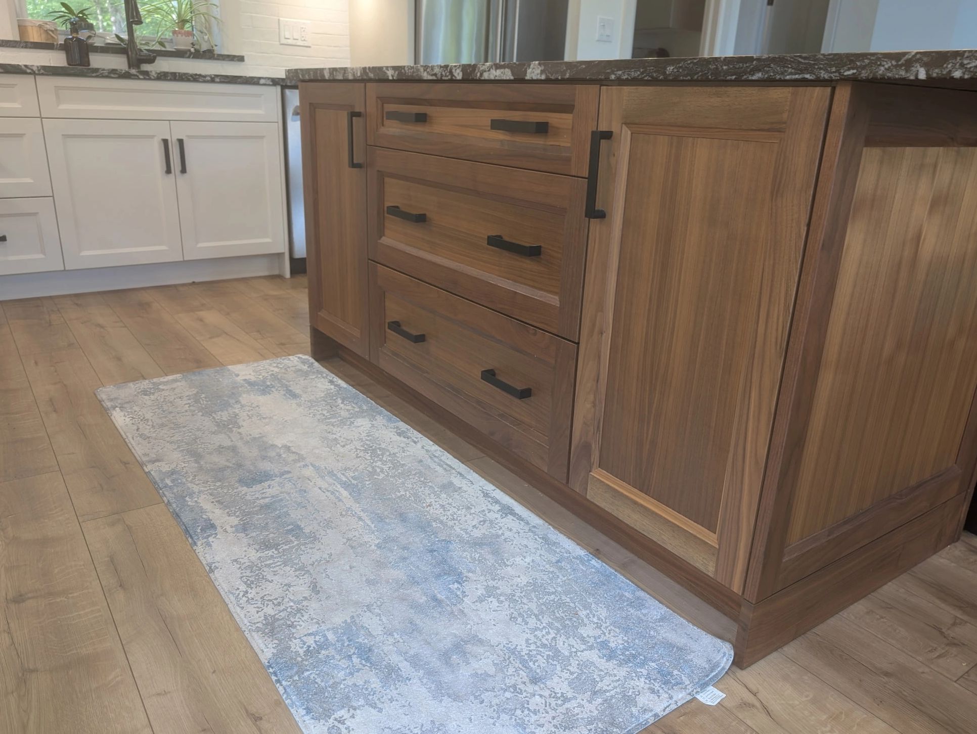 Modern kitchen with two-tone cabinets and a blue rug.