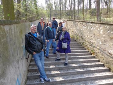 A group of people posing on outdoor stone stairs in a wooded area.