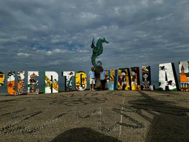 Colorful "Puerto Vallarta" letters with a seahorse statue and two men standing in the middle.