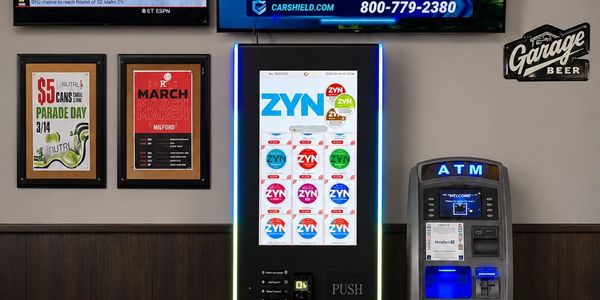 A vending machine for ZYN nicotine pouches next to an ATM in a bar setting.