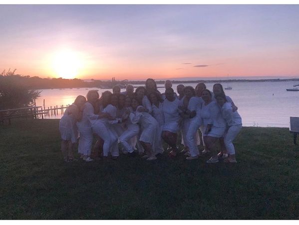 Group of women embracing, wearing white clothes on the beach
