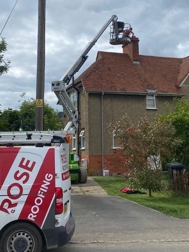 Rose Roofing Van & Cherry Picker with roofer doing a repair.