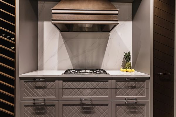 Marble backsplash with wood kitchen hood vent. Custom cabinet design