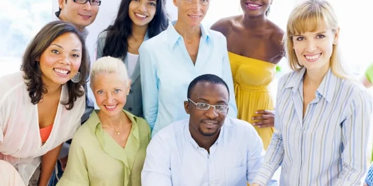 A diverse group of smiling professionals posing together indoors.