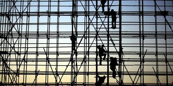 evening, the workers are climbing the silhouette of scaffolding in the high altitude