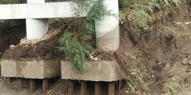 Bridge supports exposed by erosion showing concrete and metal piles.