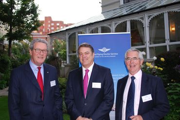 Three men in suits posing outdoors at a Royal Flying Doctor Service event.