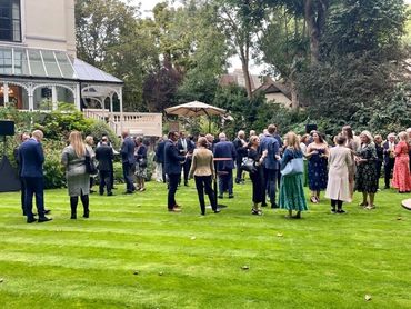 People socializing outdoors on a green lawn near a building.