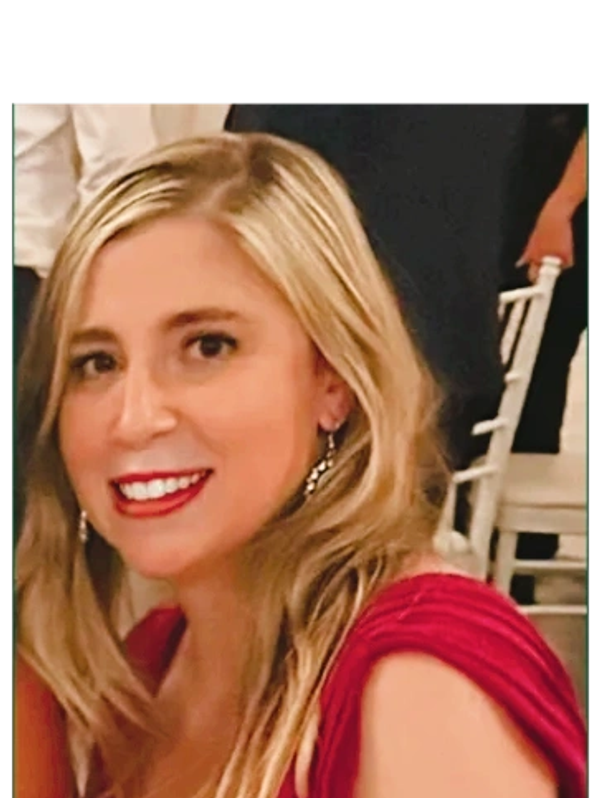 Smiling woman with blonde hair and red dress at an event.