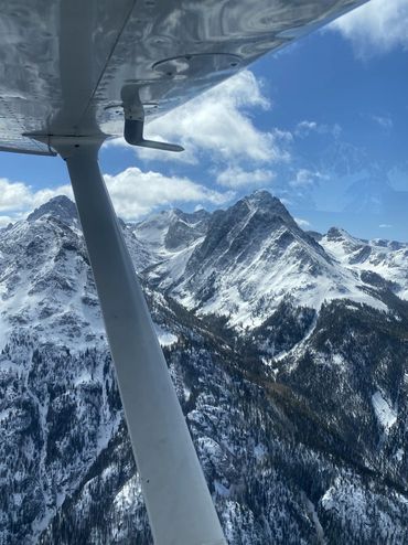 Snow-covered mountain peaks viewed from a small airplane wing.