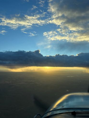 Sunset view from an airplane with dramatic clouds and golden light.