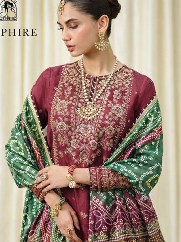 Elegant woman in traditional embroidered attire with matching jewelry and dupatta.