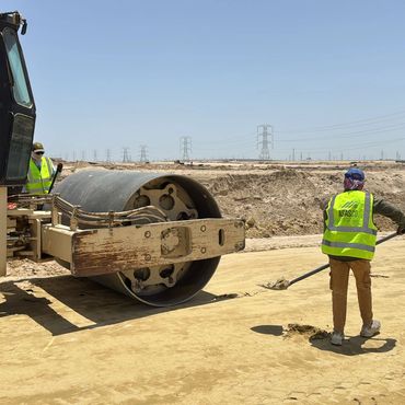 Construction workers operating heavy machinery and preparing the ground at a desert site.