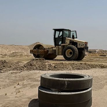 Construction site with heavy machinery and workers preparing the ground.