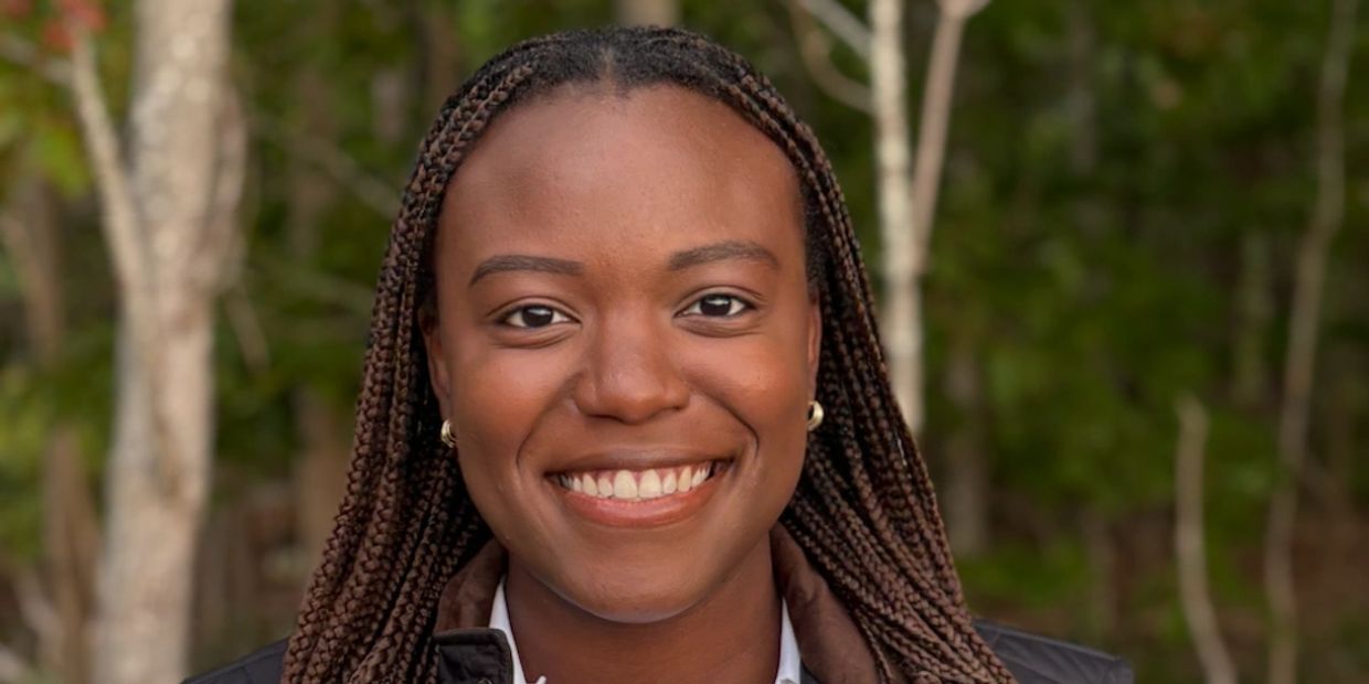 Smiling woman with braided hair outdoors.