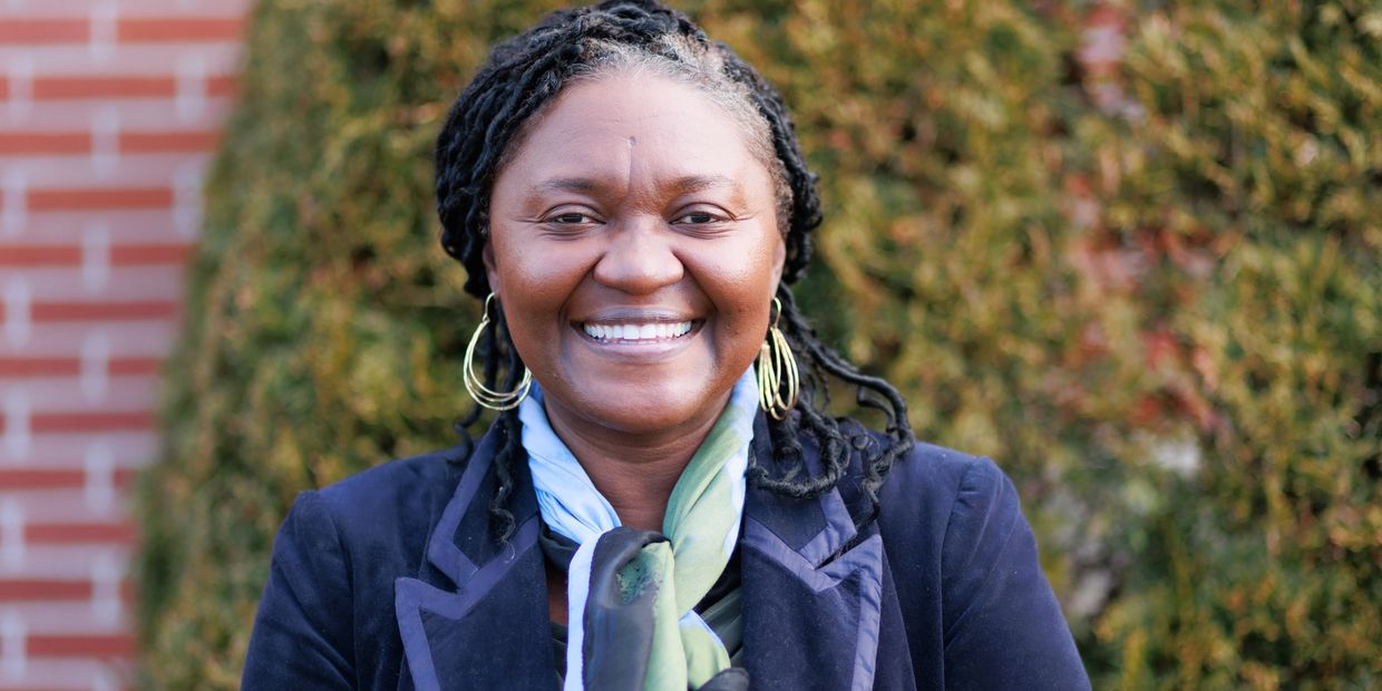Smiling woman in a blue jacket and scarf outdoors.